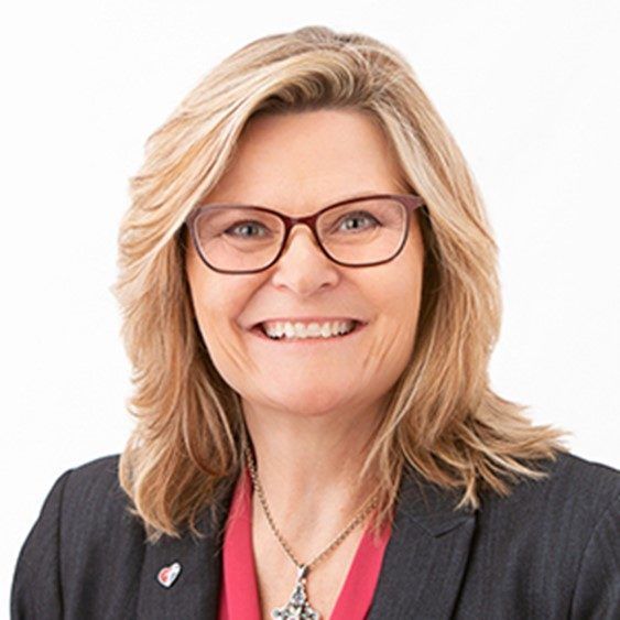 Smiling professional wearing glasses and a dark blazer on a white background