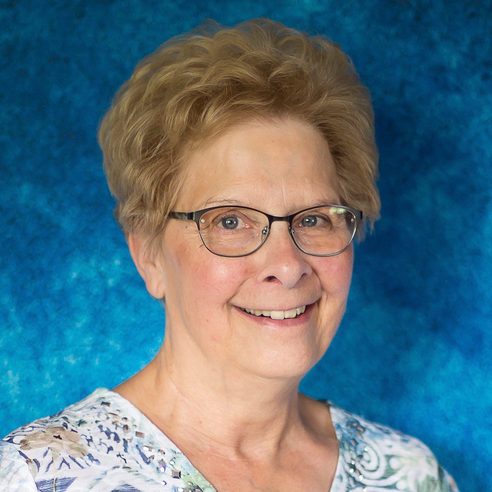 Portrait of a smiling woman with glasses against a blue background