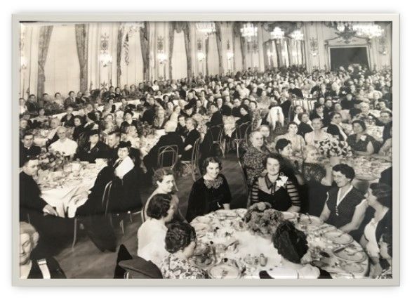 Large banquet hall filled with seated guests at round tables, attending a formal dinner event