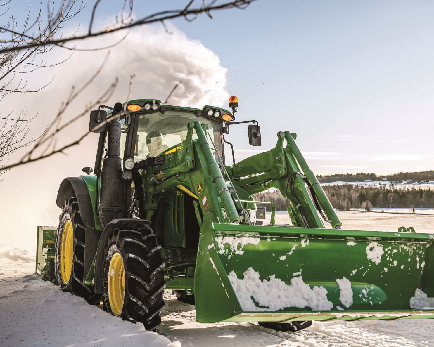 John Deere 6000 series tractor plows a road with a front loader attachment