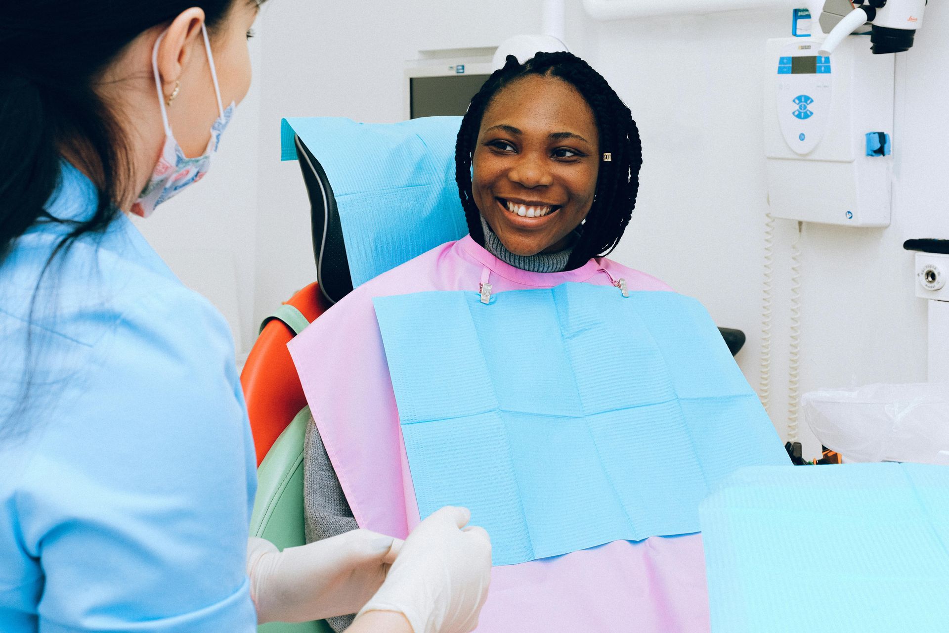 Dentist showing a patient their teeth in a mirror. Both are smiling in a bright dental office.