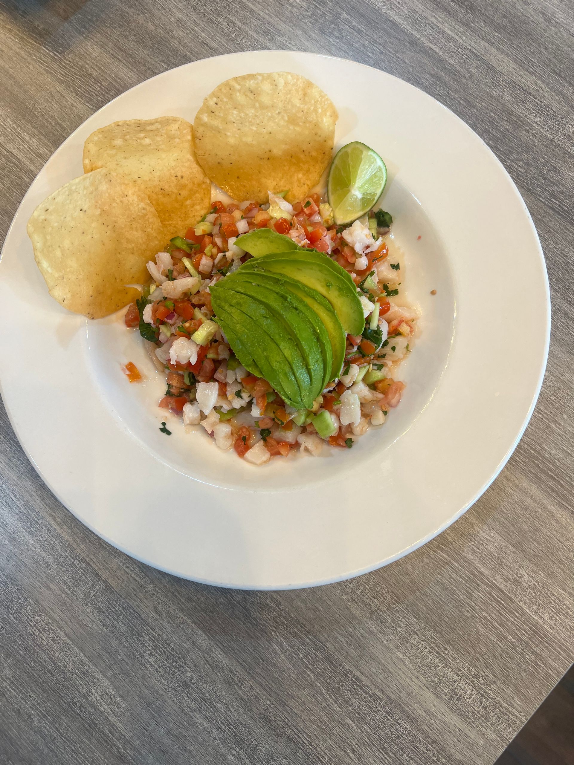 A plate of food with avocado and chips on a table.