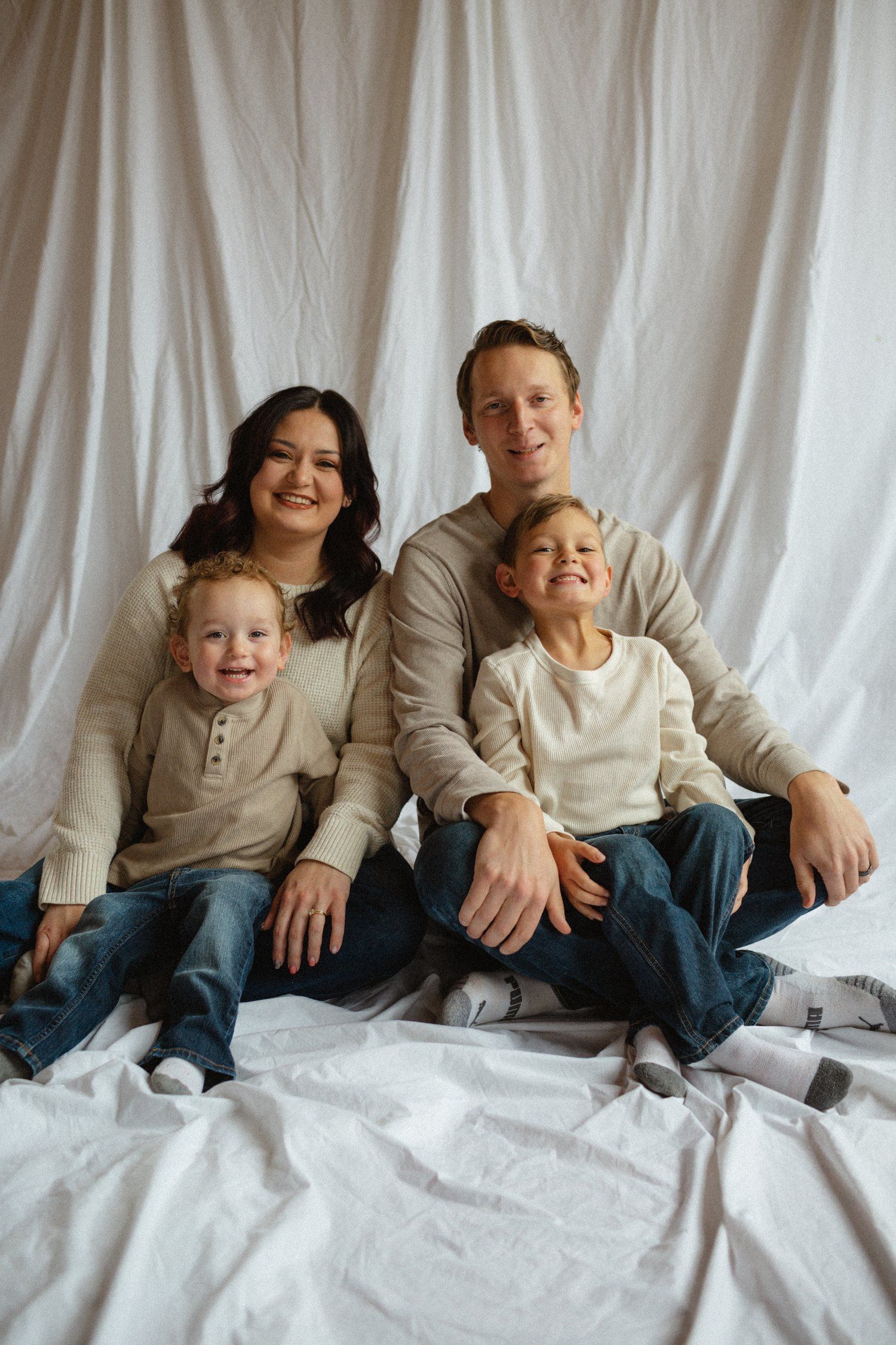 A family is posing for a picture while sitting on a bed.