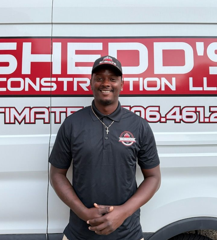 Man in black polo standing in front of a white truck with red construction company lettering