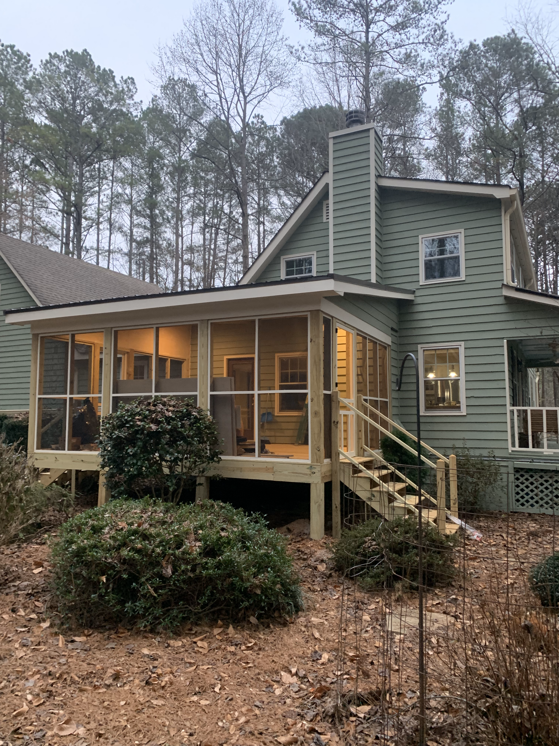 A green house with a screened in porch and stairs