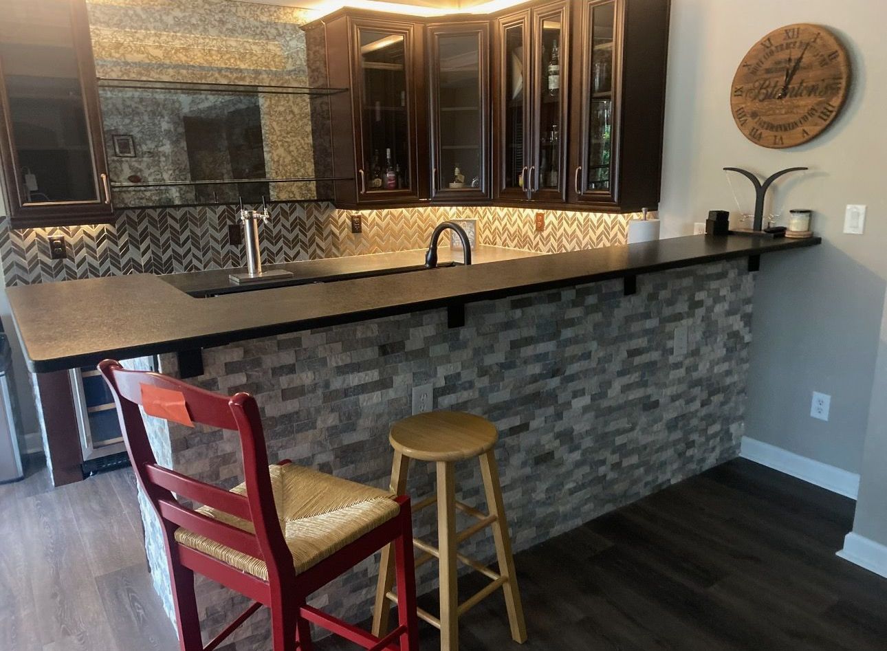 A kitchen with a bar and a clock on the wall