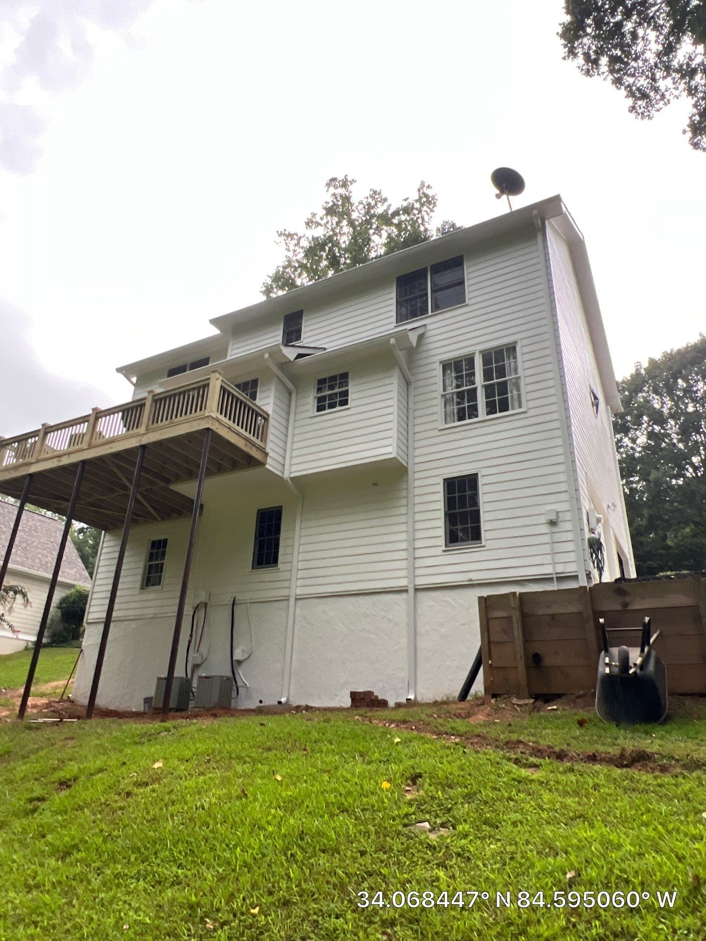 White three-story house with porch and exterior stairs on a grassy lot, viewed from below