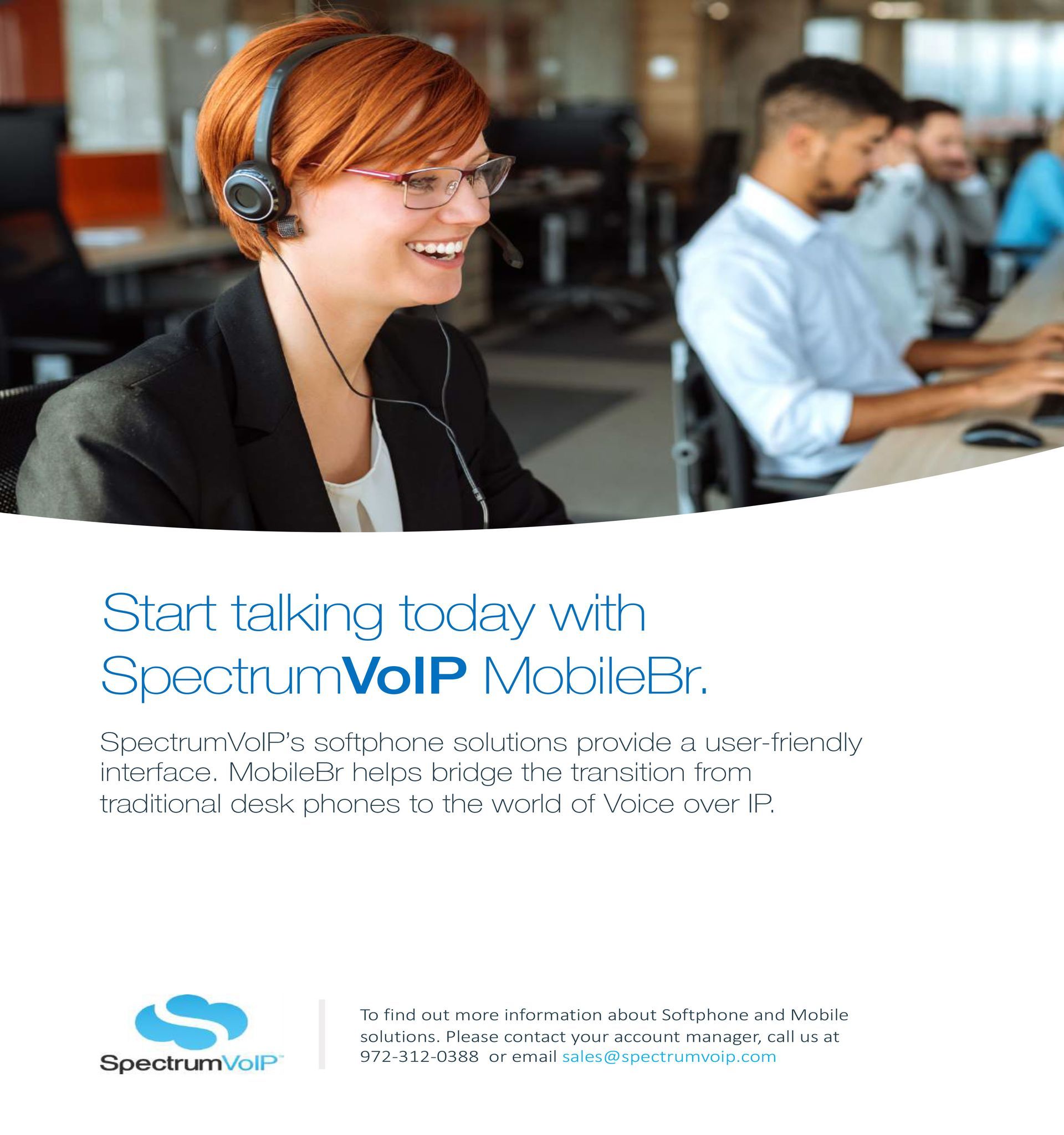A woman wearing headphones is smiling while sitting at a desk in a call center.