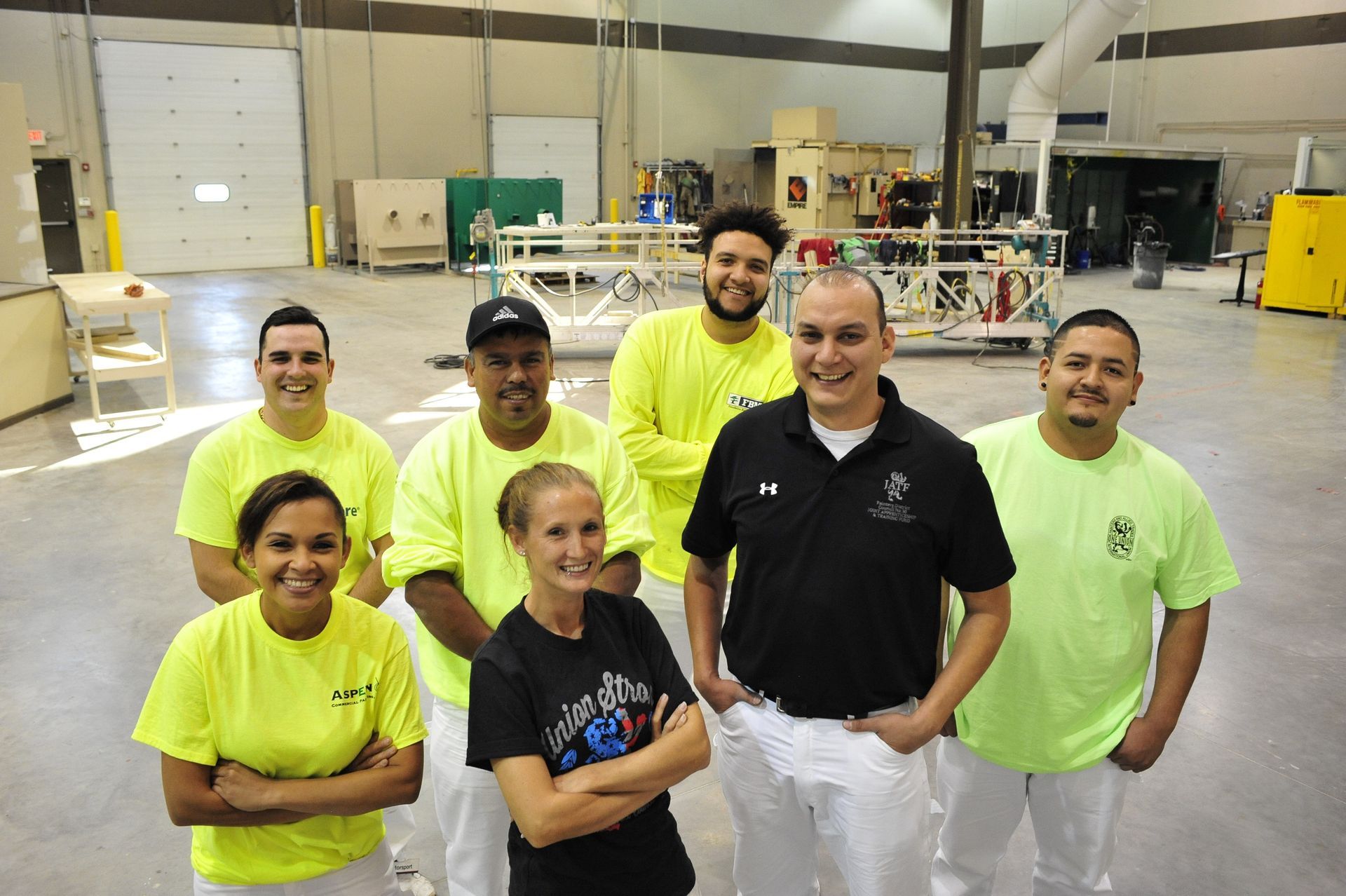 A group of painting apprentices and instructors smiling together in the training facility.