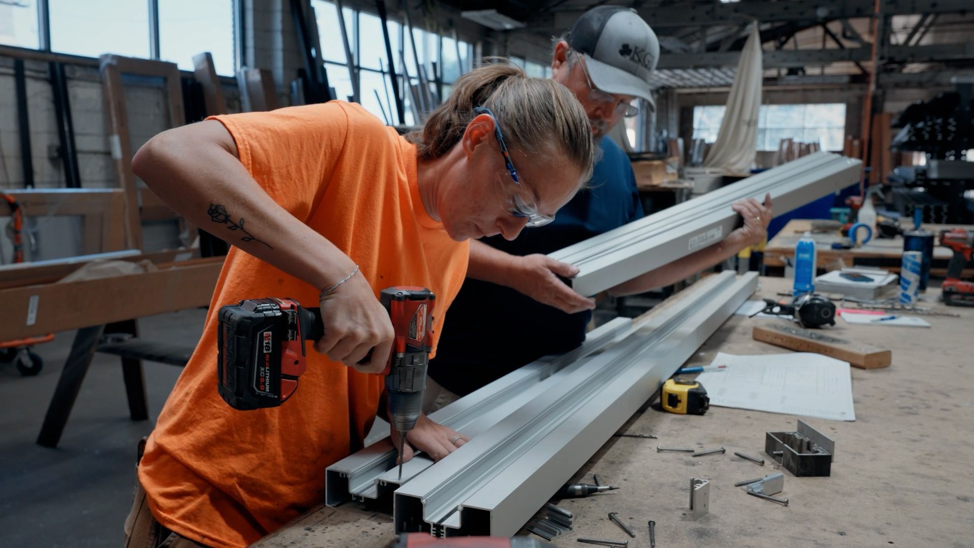 A NCIFTI glazier using a power drill to assemble a professional storefront framing system.