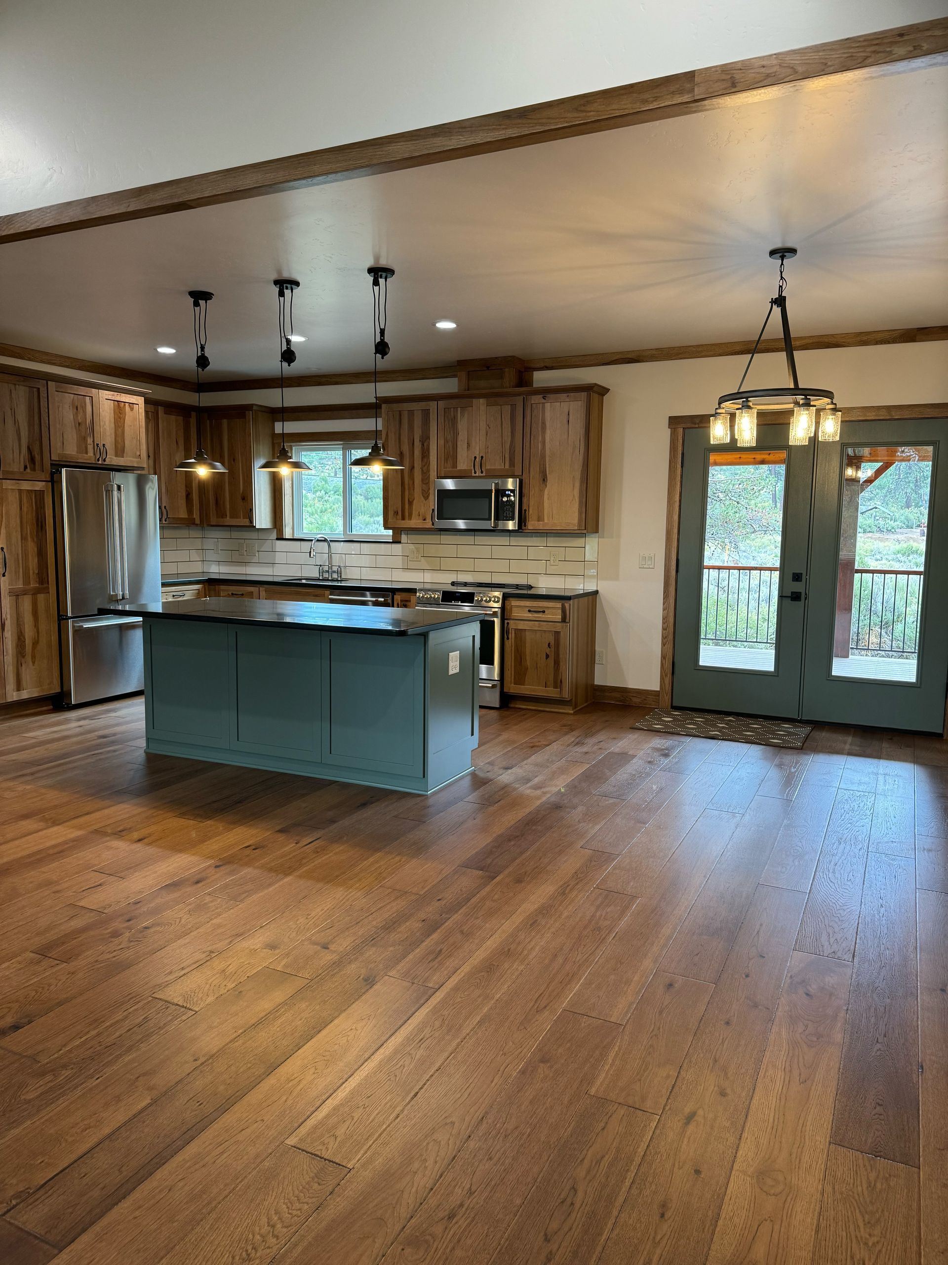 Spacious rustic kitchen and dining area with hardwood floors, blue island, stainless appliances, and French doors.