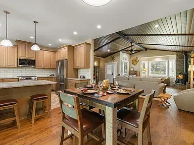 Open kitchen and dining area with wood cabinets, island stools, and a vaulted ceiling
