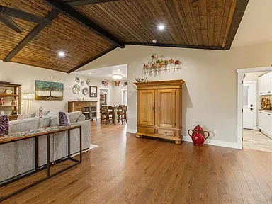 Spacious open living room with wood ceiling, hardwood floors, and a large wooden cabinet.