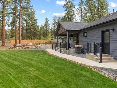 Modern gray house with covered porch and manicured lawn in a wooded yard