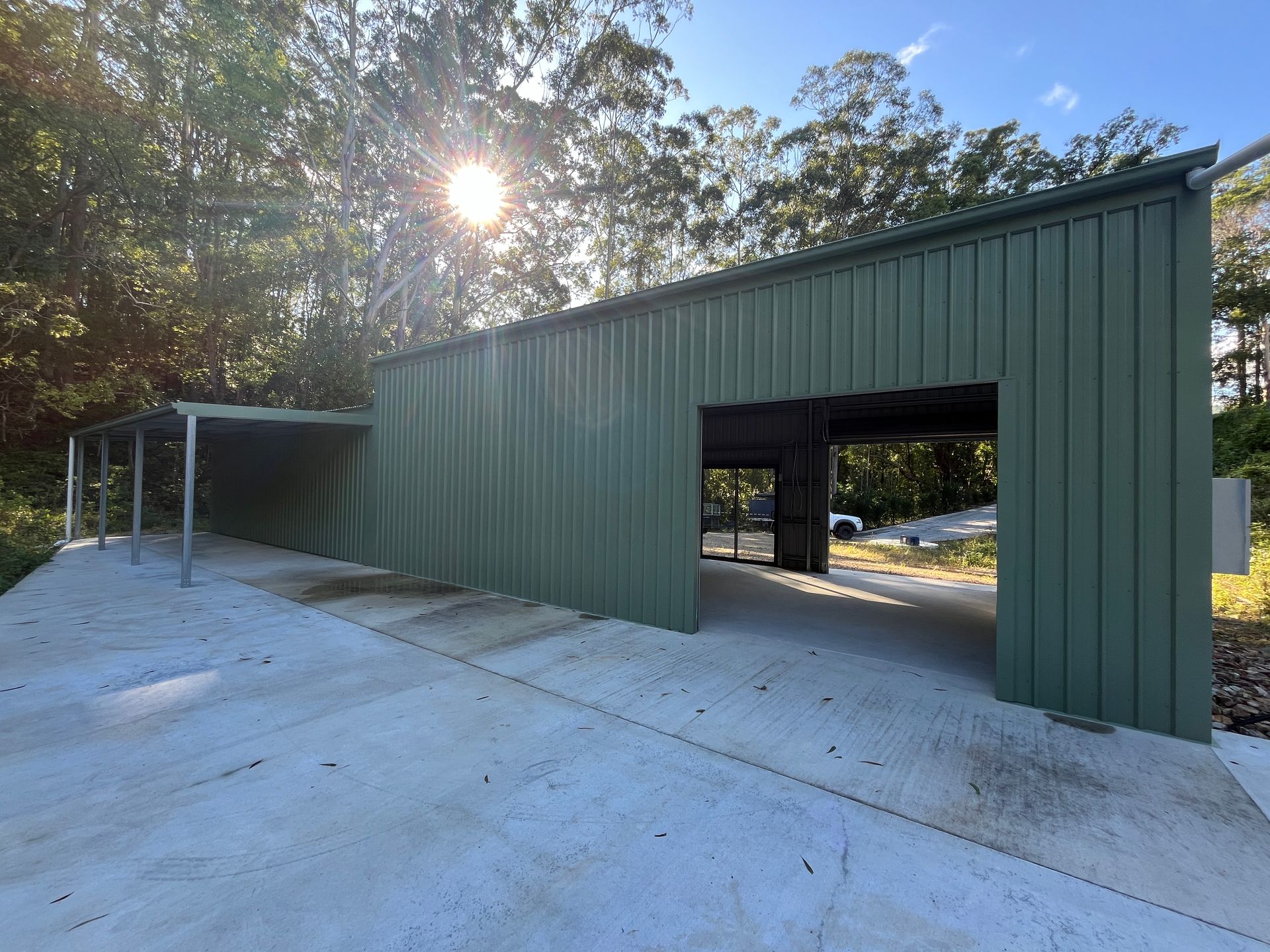 The Sun is Shining Through the Trees Behind a Green Shed — Urbon Sheds in Uki, NSW