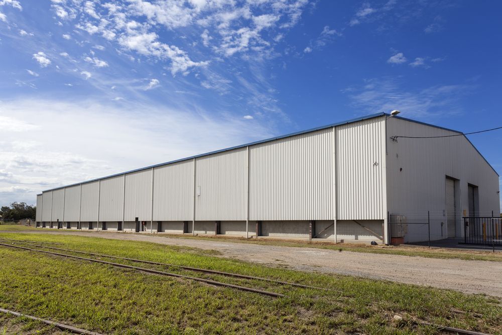 A Large White Building is Sitting in the Middle of a Grassy Field — Urbon Sheds in Mullumbimby, NSW
