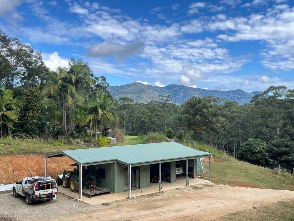 A Tractor is Parked In Front of a House with Mountains in the Background — Urbon Sheds in Uki, NSW