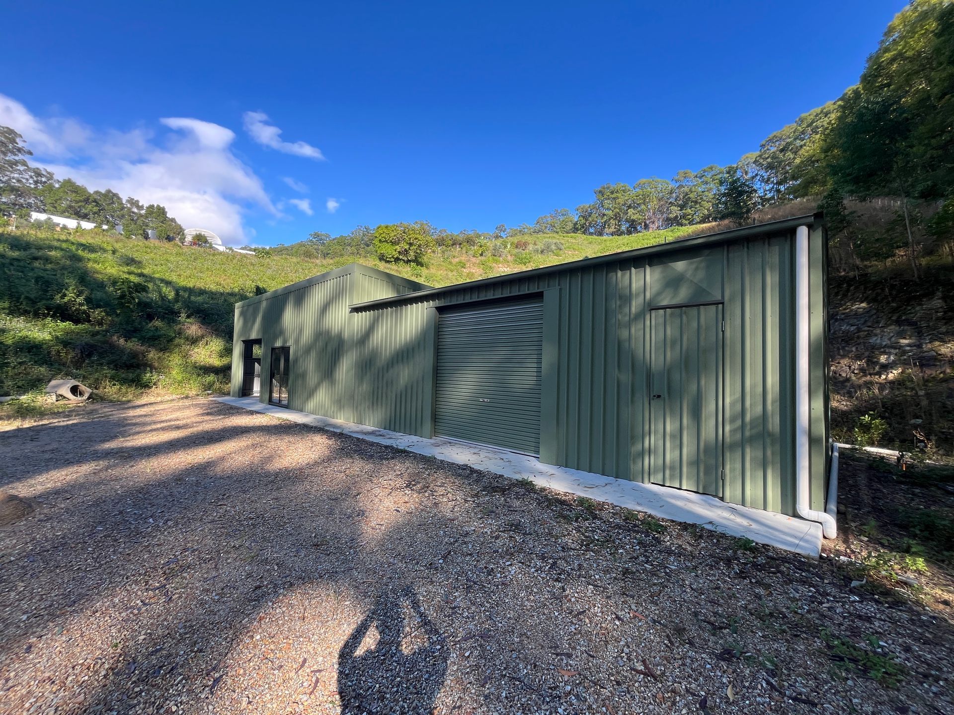 A Green Shed is Sitting on the Side of a Gravel Road — Urbon Sheds in Uki, NSW
