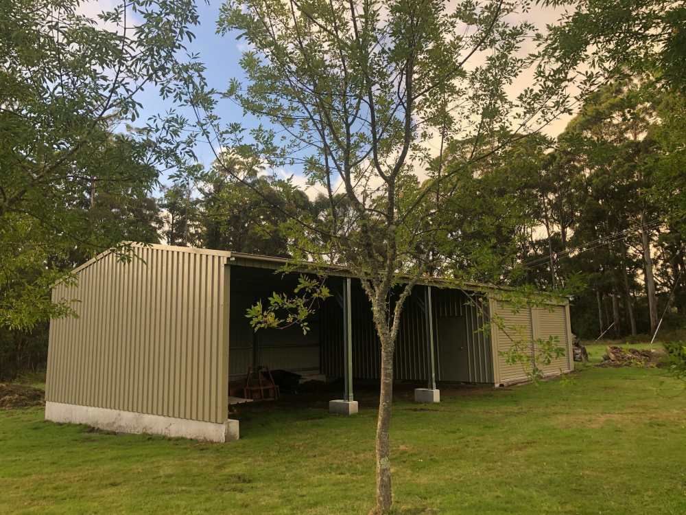 A Garage With a Gray Garage Door is Sitting on Top of a Gravel Driveway — Urbon Sheds in Banora Point, NSW