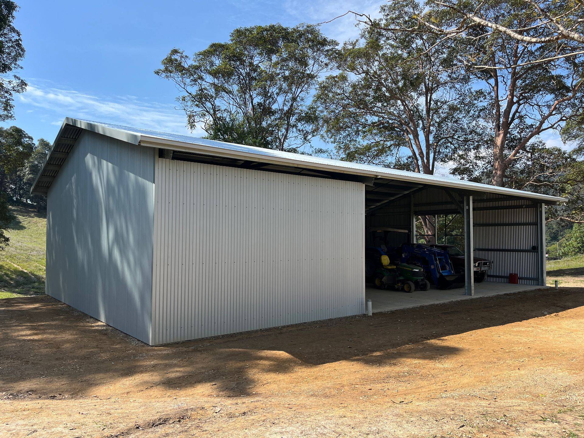 A Green Metal Sheds With A Concrete Driveway And Trees In The Background — Urbon Sheds in Mullumbimby, NSW