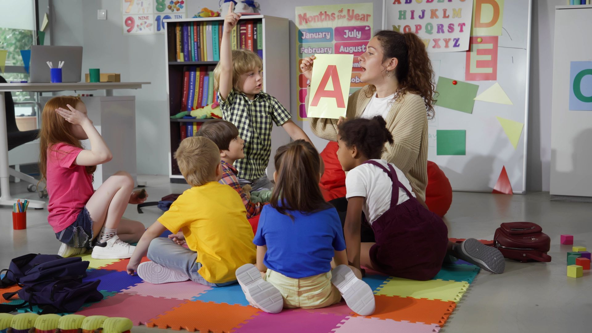 A teacher is talking to a group of kids. Preschool education teacher leading children in an interactive alphabet learning circle activity.