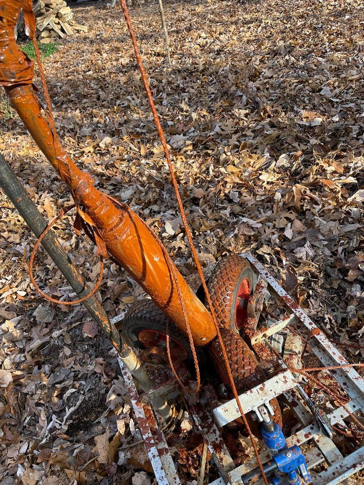 A rusty object is laying on the ground in the woods.