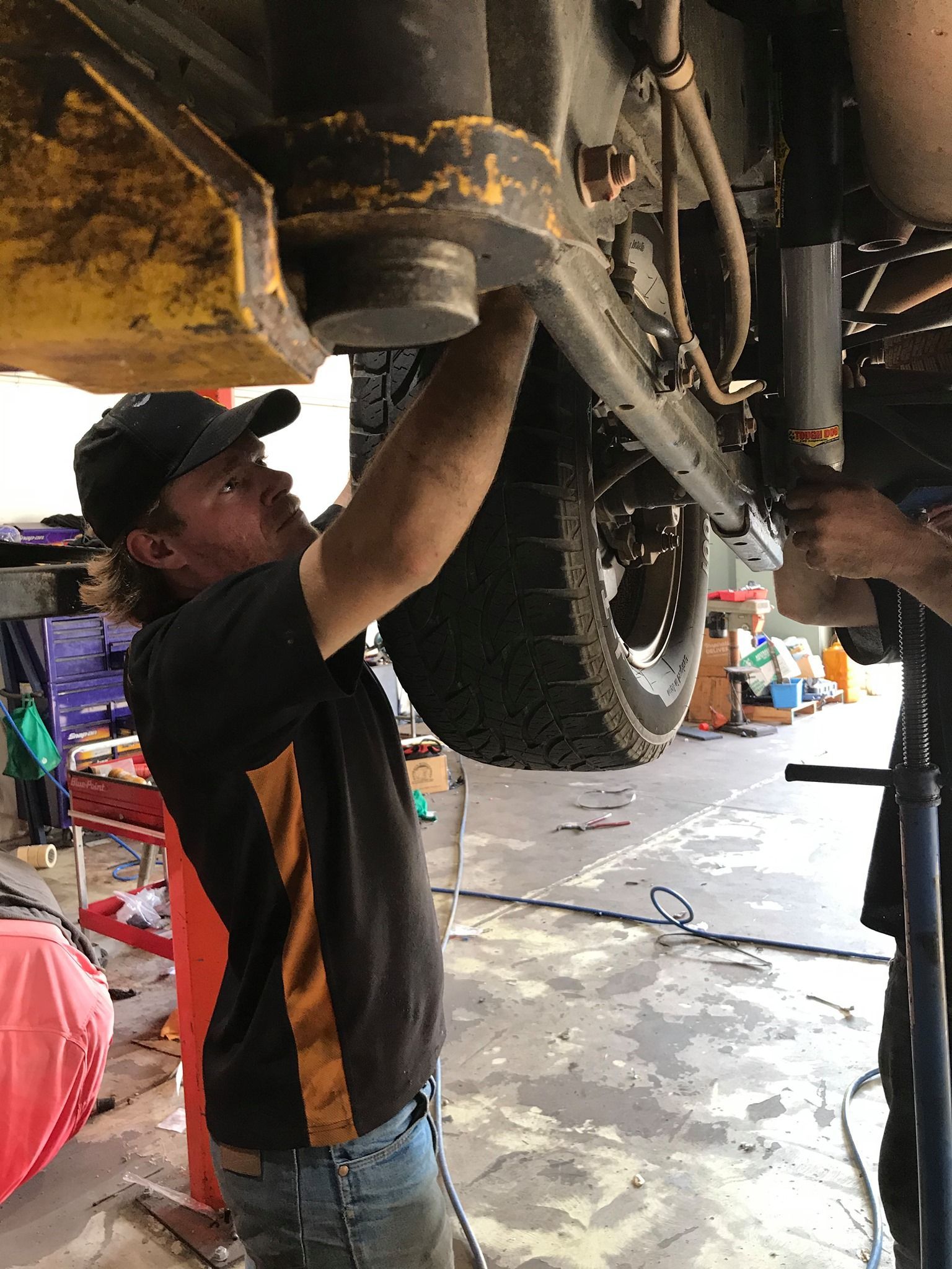 Blue suspension coil on a black vehicle frame, showing mechanical parts — Stay on Track 4X4 Accessories in Gladstone Central, QLD