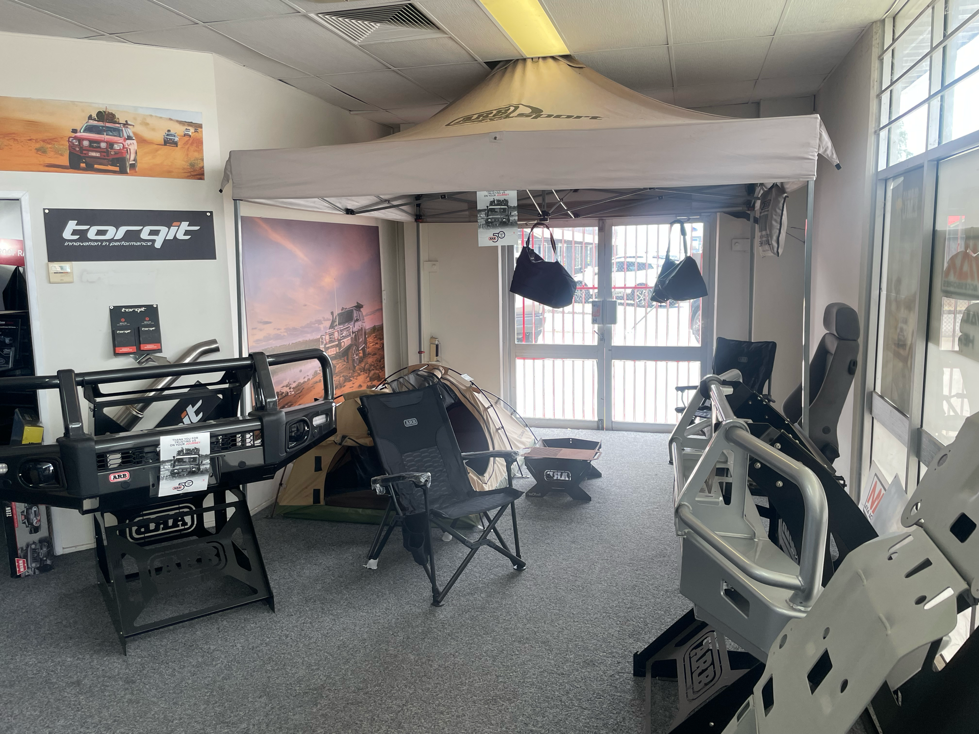 Small workshop garage with a race car frame, folding chairs, tools, and overhead lights — Stay on Track 4X4 Accessories in Gladstone Central, QLD