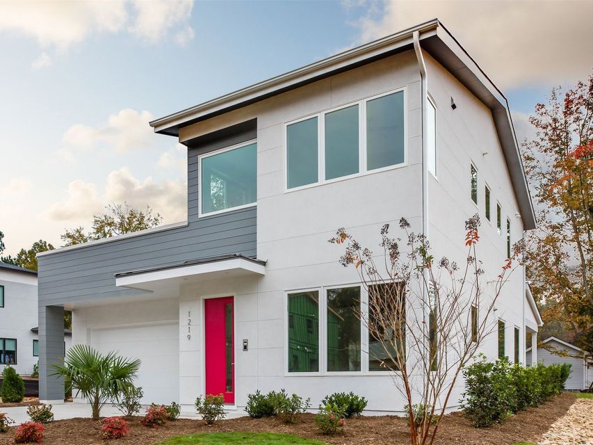 Modern two-story white house with pink front door and large windows on a landscaped lot