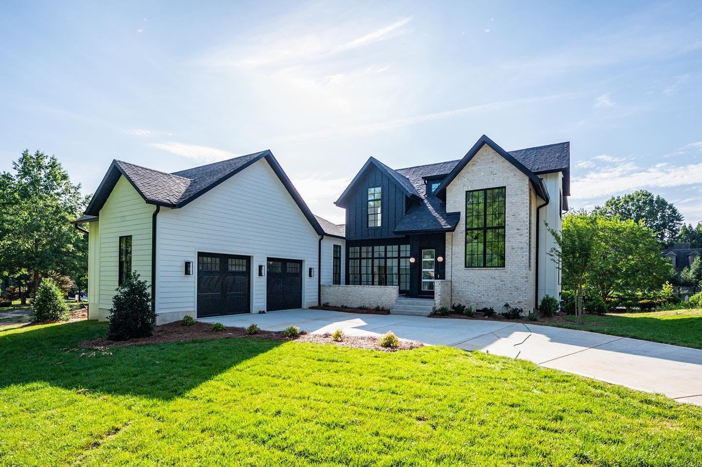 A large white house with a black roof is sitting on top of a lush green lawn.