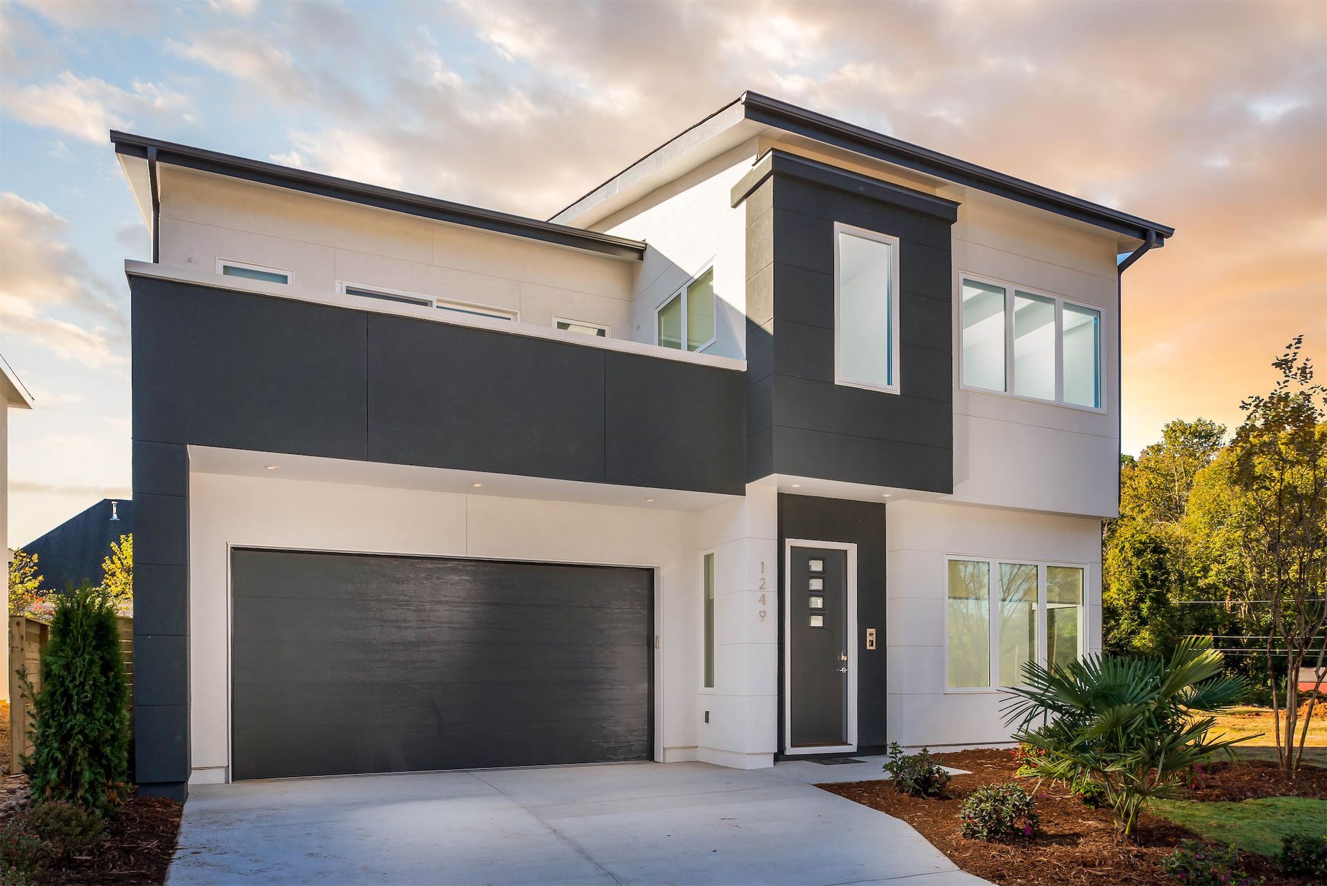 A black and white house with a garage and a driveway.