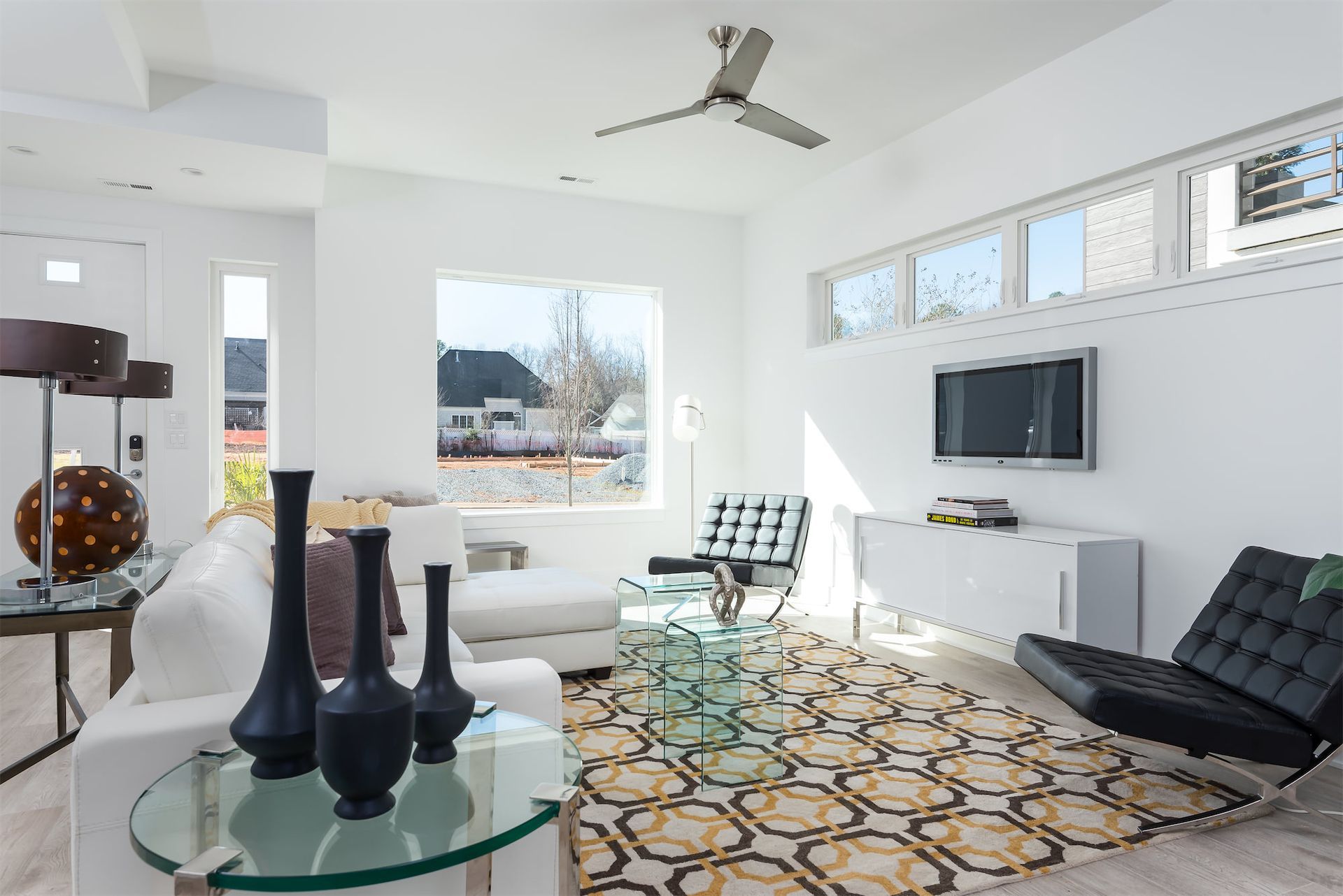 A living room with a ceiling fan and a flat screen tv