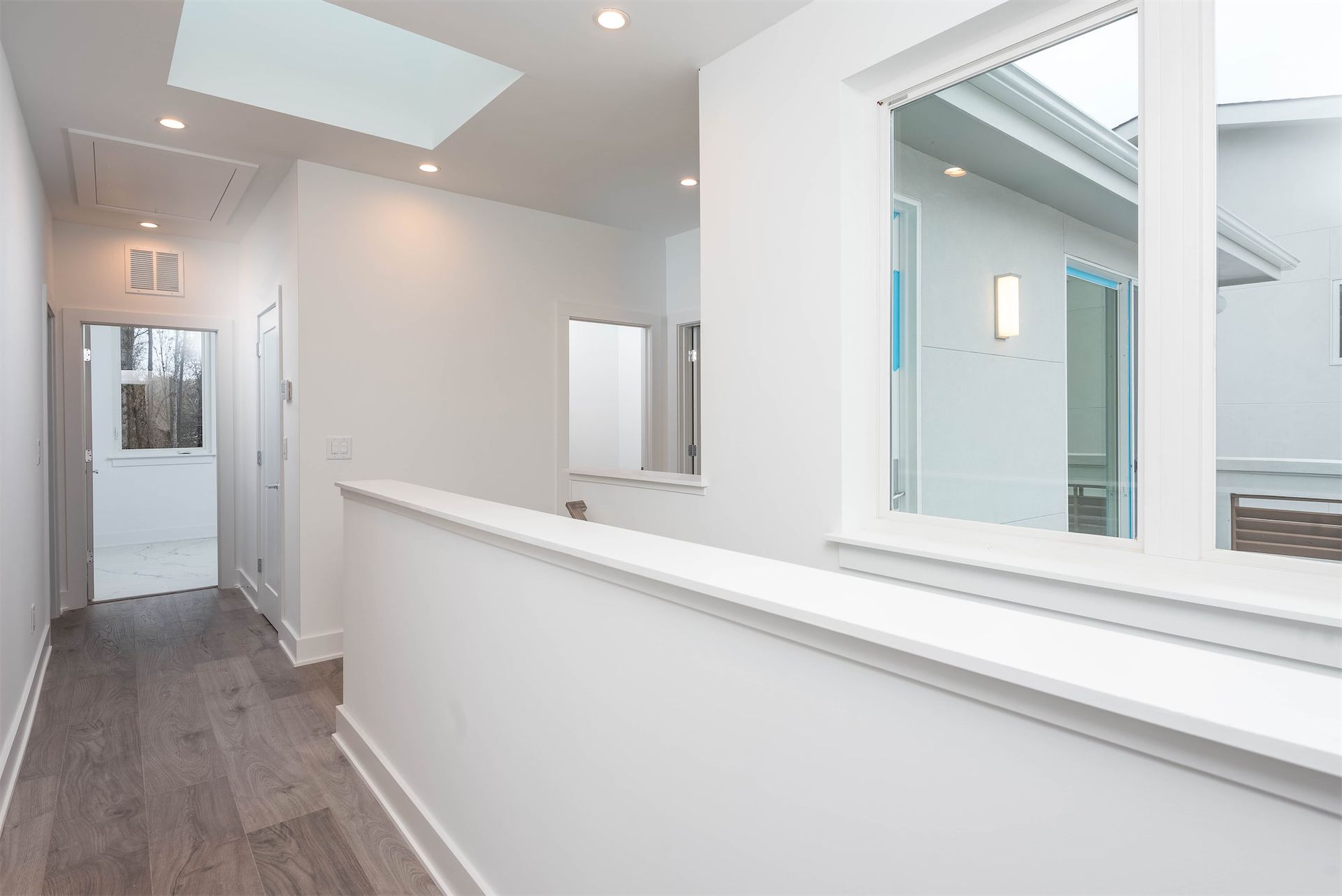 A hallway in a house with a skylight and a window.