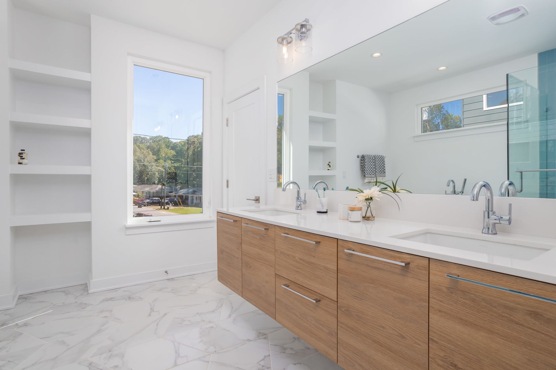 A bathroom with two sinks , a large mirror and a window.