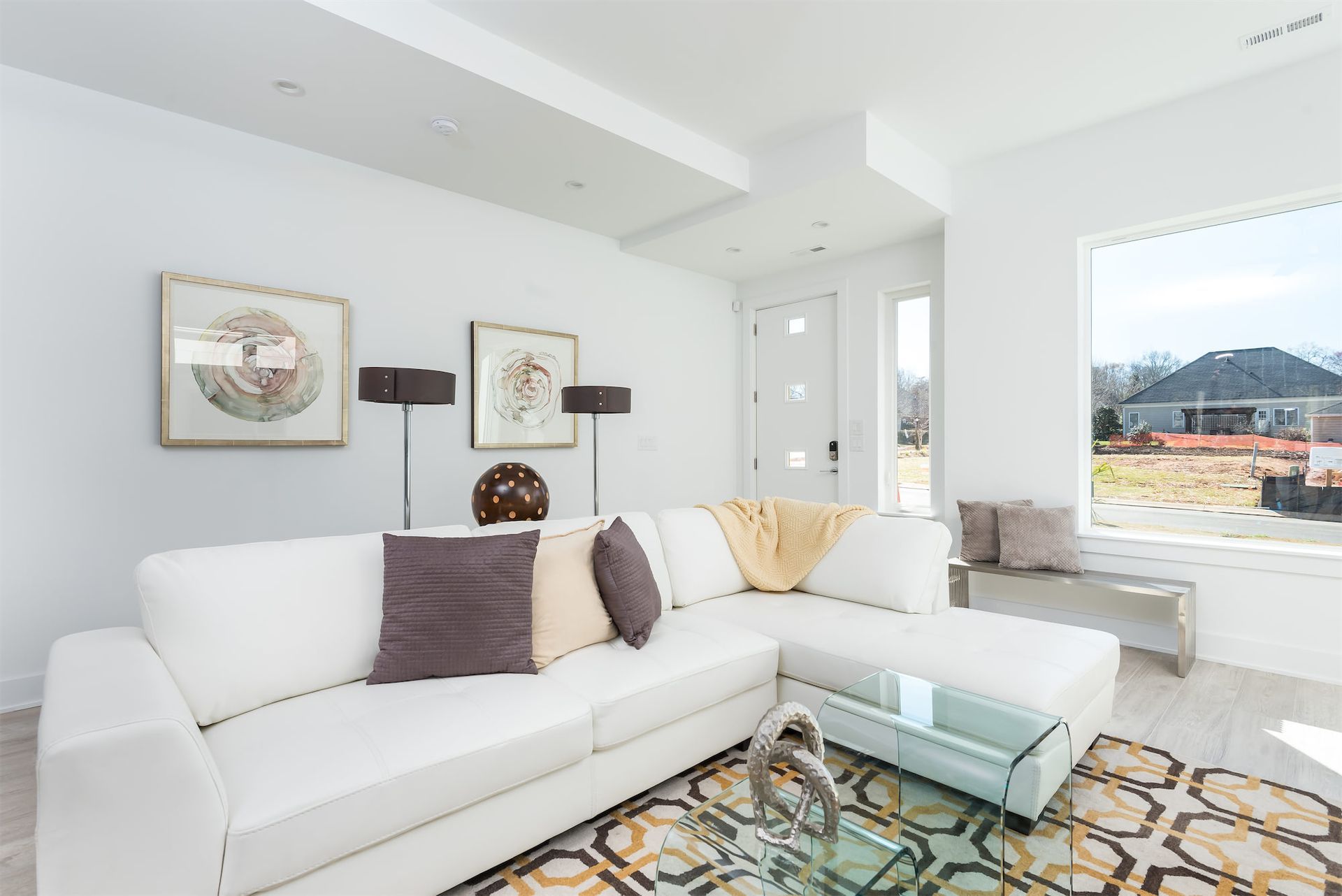 A living room with a white sectional couch and a glass coffee table.