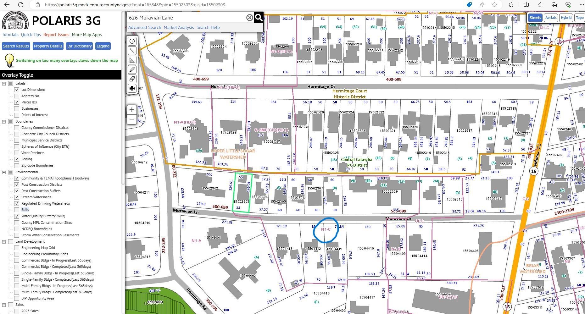 Map interface of a neighborhood with building outlines, streets, and a highlighted route or boundary line.