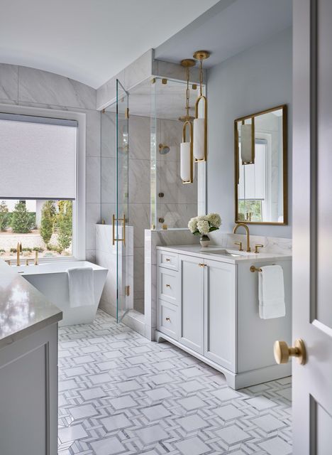 Bright, elegant bathroom with white vanity, glass shower, and large window with a view.