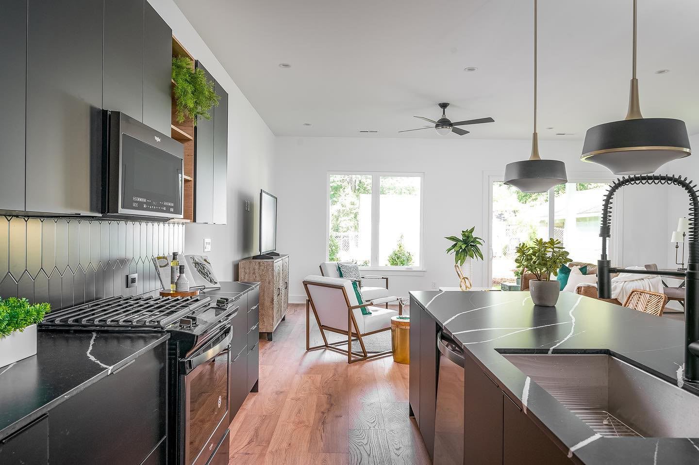 a kitchen with black cabinets , stainless steel appliances , a sink and a stove .