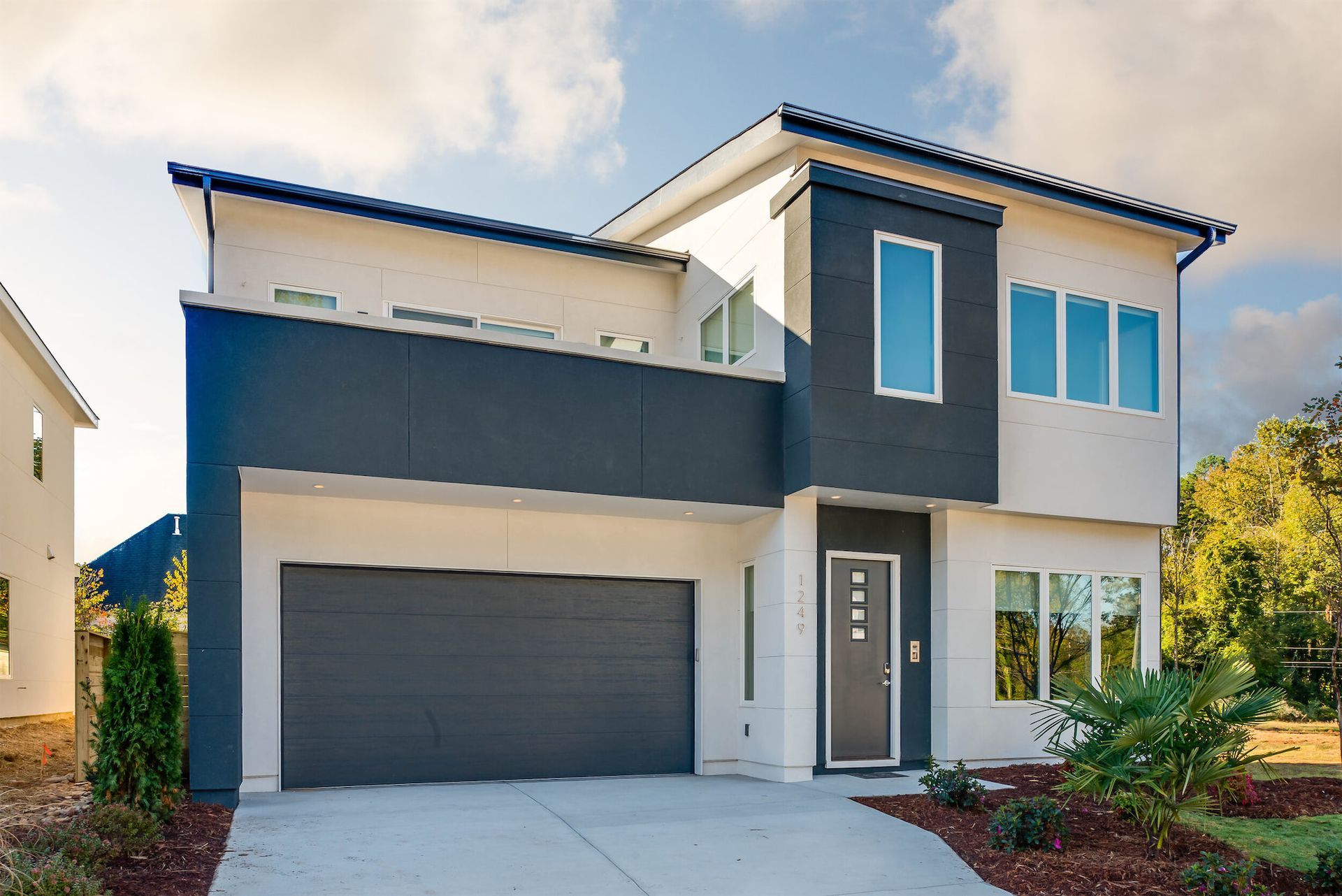 Modern two-story house with gray and white exterior, garage, and front entry driveway