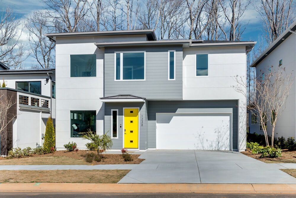 A modern house with a yellow door and a white garage door.