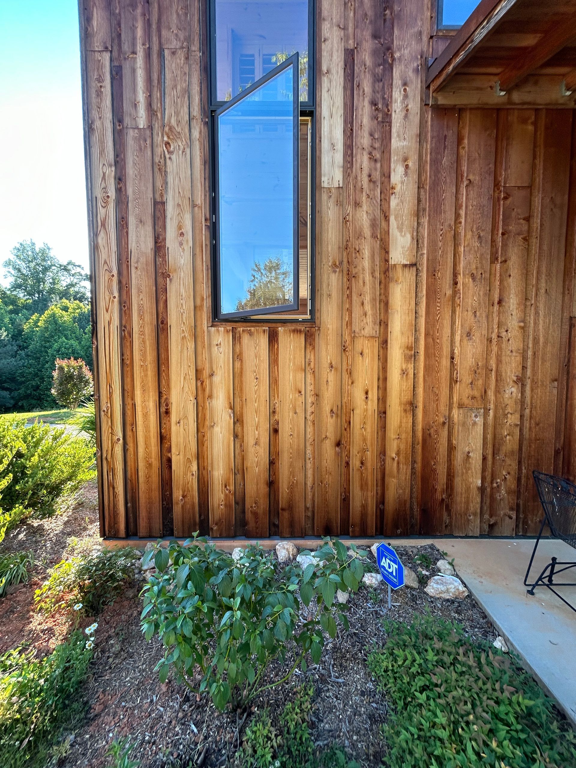 A wooden house with a large window on the side of it.