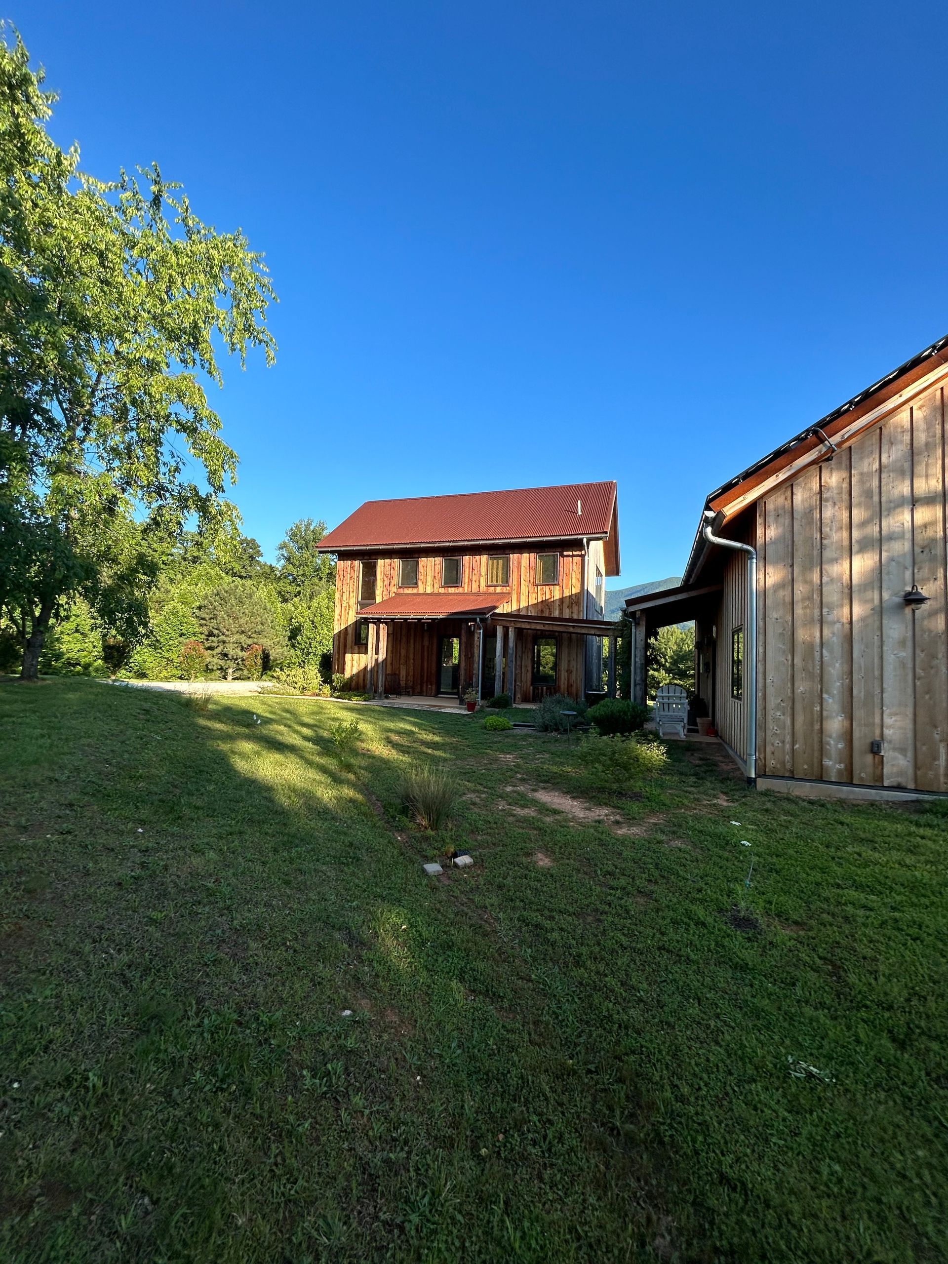 A large house with a red roof is sitting in the middle of a grassy field.