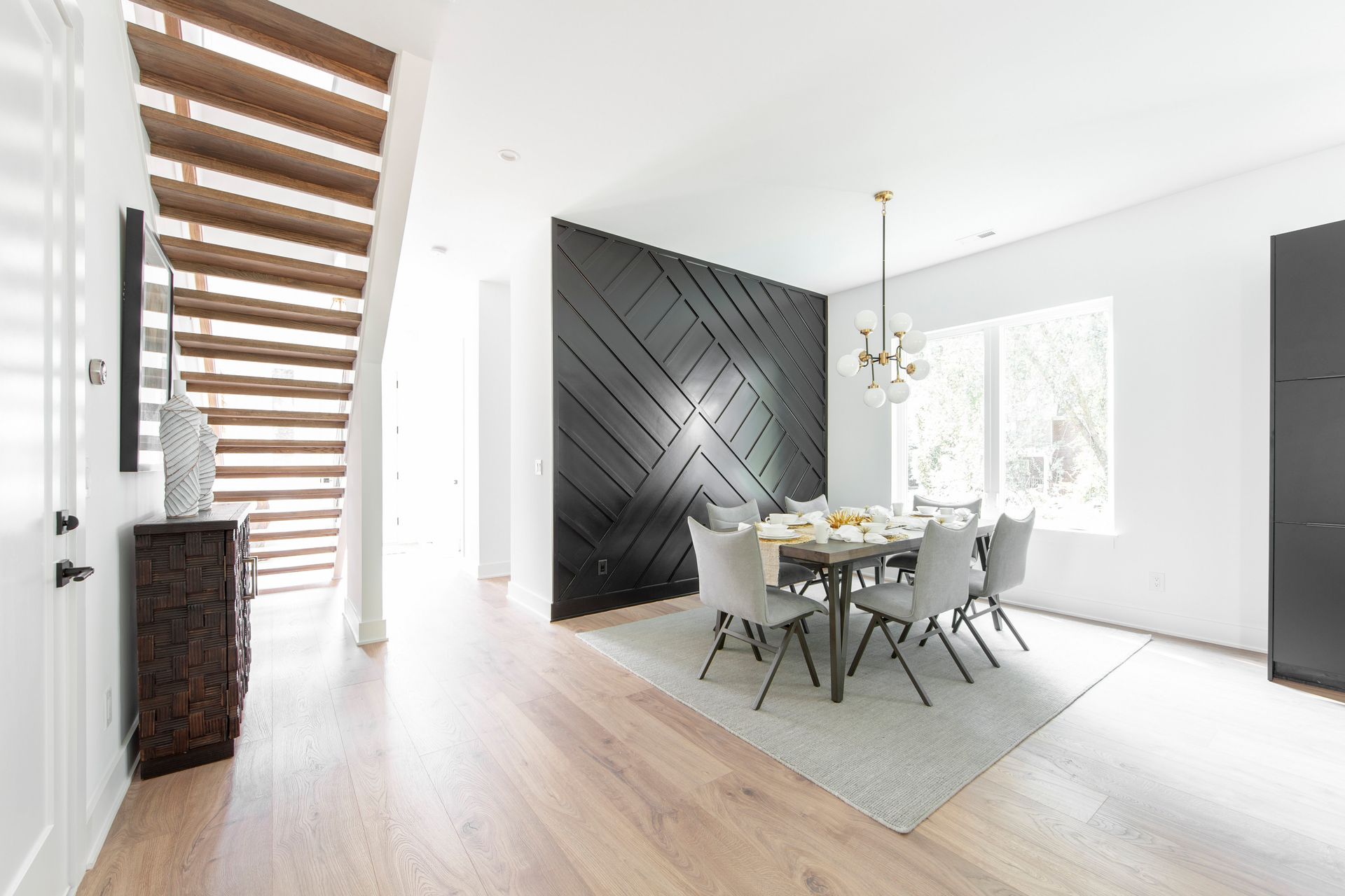 A dining room with a table and chairs and a black wall.