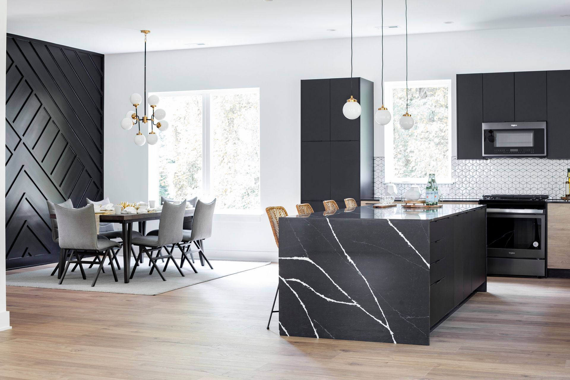 A kitchen and dining room in a house with black cabinets and a large island.