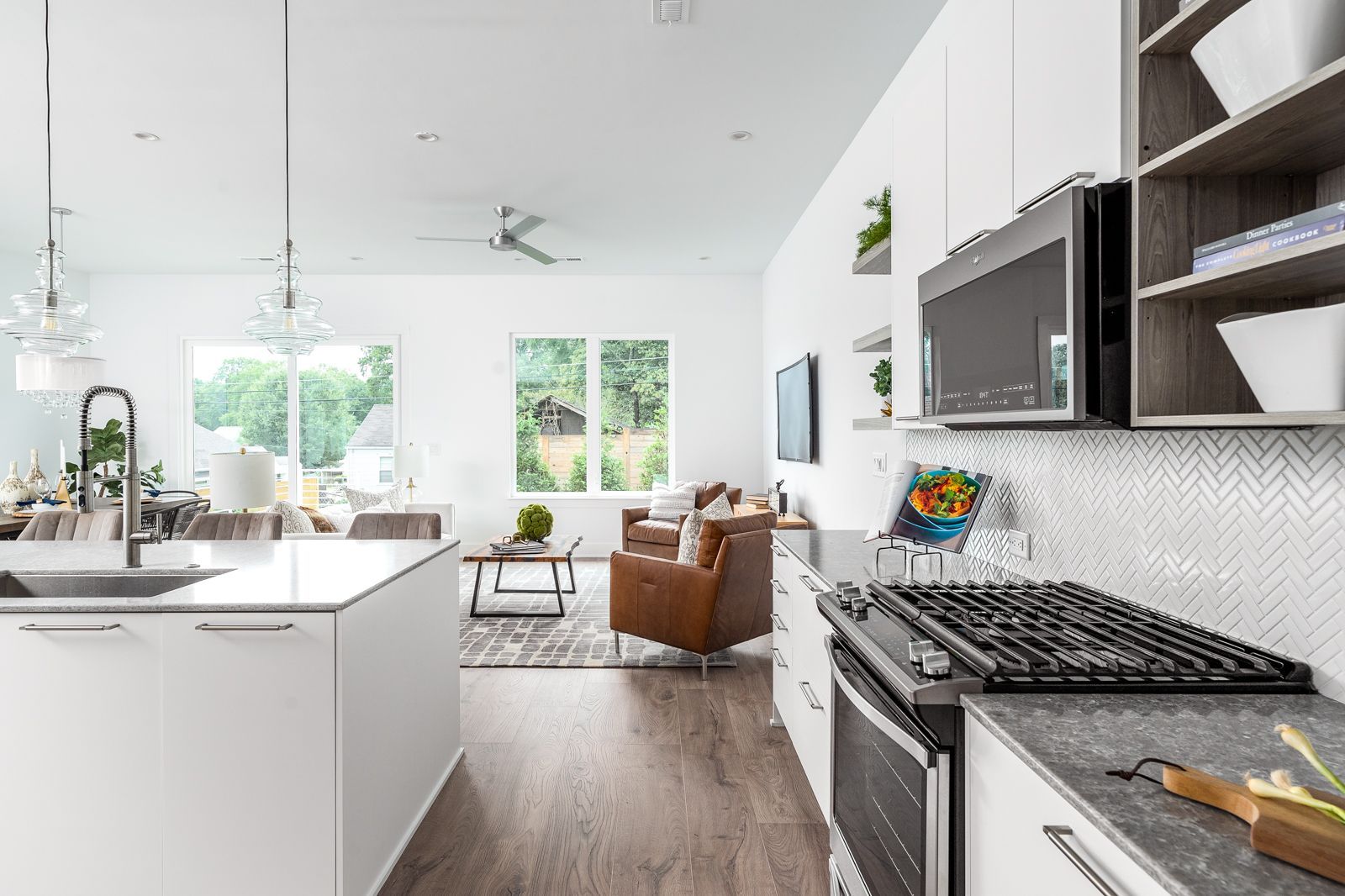 A kitchen with white cabinets , a stove , a microwave and a sink.