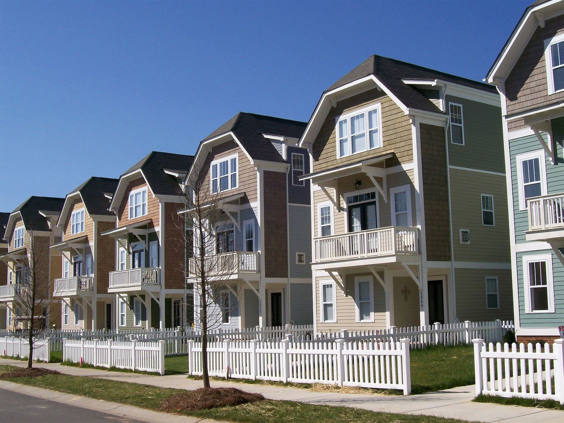 A row of houses with a white picket fence in front of them