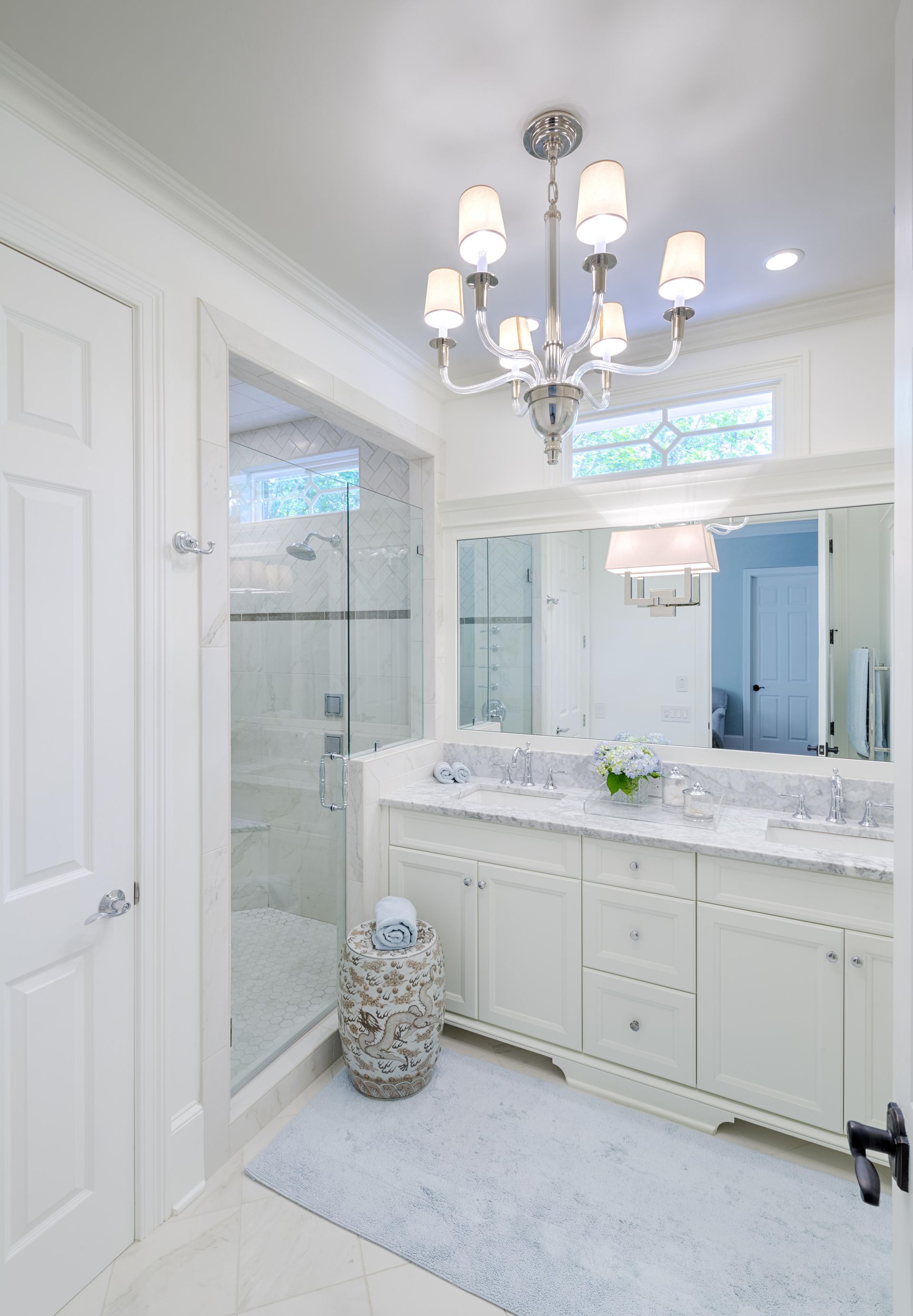 A bathroom with two sinks , a mirror and a chandelier.