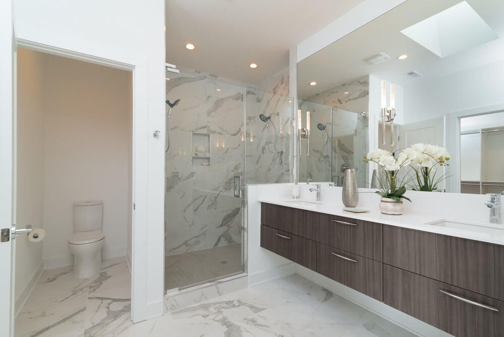 A bathroom with two sinks , a toilet , and a walk in shower.
