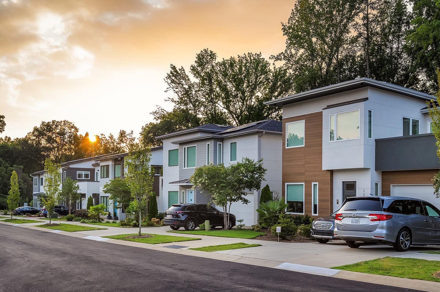 A row of houses with cars parked in front of them