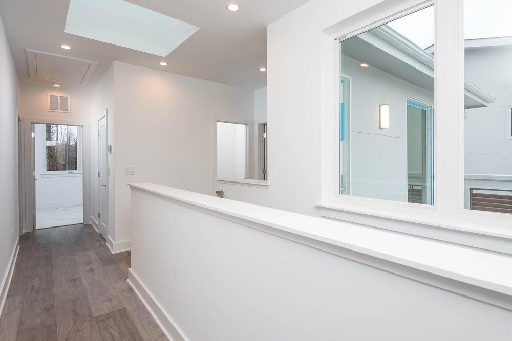 A hallway in a house with a skylight and a window.